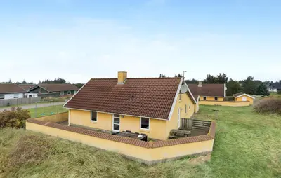 a small yellow house with a brown roof on a field at Beautiful Home In Thisted With Sauna in Thisted