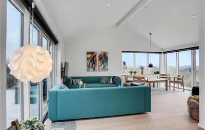a living room with a blue couch and a table at Five-Bedroom Holiday Home Løkken With A Room Hot Tub 04 in Løkken