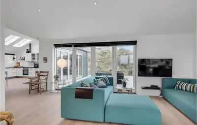 a living room with a blue couch and a kitchen at Five-Bedroom Holiday Home Løkken With A Room Hot Tub 04 in Løkken