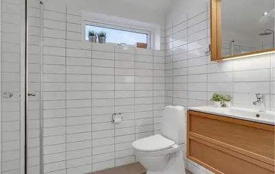 a white bathroom with a toilet and a sink at Five-Bedroom Holiday Home Løkken With A Room Hot Tub 04 in Løkken