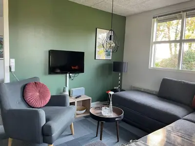 a living room with two couches and a tv at Aneks i rolige omgivelser-adgang til pool og sauna in Avlum