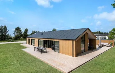 a house with a black roof on a wooden deck at Cozy Home In Saltum With Sauna in Saltum