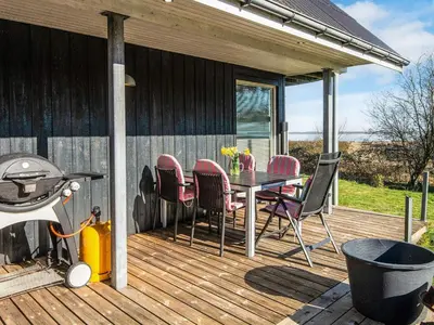 a deck with a table and chairs and a grill at Panoramic Fjord Retreat with Spa Bath in Øster Assels