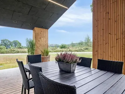 a wooden table with chairs and a potted plant on a deck at 5 star holiday home in Skals in Skals