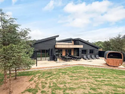 a black house with a patio and a yard at 5 star holiday home in Højslev in Højslev