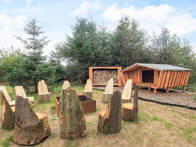 a group of wooden stump chairs and a cabin at 5 star holiday home in Højslev in Højslev