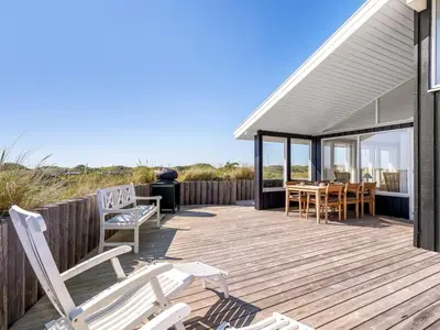 a wooden deck with chairs and a table on the beach at Holiday Home Naema - 400m from the sea by Interhome in Blokhus