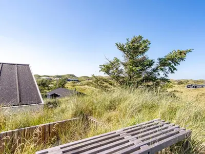 a bench sitting in the grass next to a building at Holiday Home Naema - 400m from the sea by Interhome in Blokhus