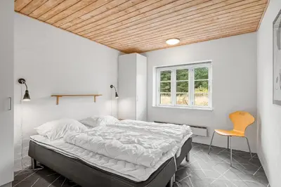 a bedroom with a bed and a chair in it at Large Pool House With Activity Room Located In Peaceful Surroundings in Frøstrup