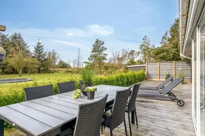 a wooden table and chairs on a wooden deck at Lovely Spa House In Scenic Surroundings in Thyholm