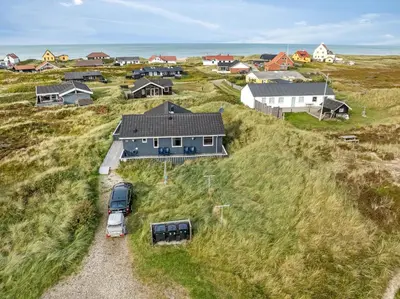 a house on a hill with a car parked in front at Holiday Home With Spa And Sauna, Just 200 Meters From The North Sea in Frøstrup