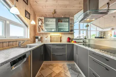 a kitchen with stainless steel appliances and wood ceilings at Holiday Home With Spa And Sauna, Just 200 Meters From The North Sea in Frøstrup