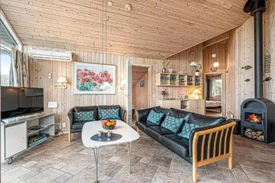 a living room with a couch and a table at Holiday Home With Spa And Sauna, Just 200 Meters From The North Sea in Frøstrup