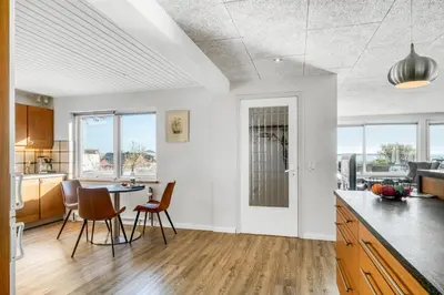 a kitchen with white walls and wooden floors and a table with chairs at Large Holiday Home With A View Of The Fjord in Thyholm