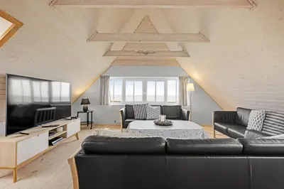a living room with a couch and a tv at Pool And Activity House With A Fantastic View Of The North Sea in Frøstrup