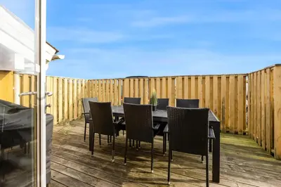a table and chairs on a deck with a fence at Pool House With Spa And Sauna, 200 Meters From The North Sea in Frøstrup