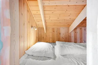 a bed in a small room with a wooden ceiling at Pool House With Spa And Sauna, 200 Meters From The North Sea in Frøstrup