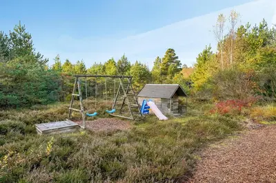 a playground in a field with a swing at Cozy And Spacious Holiday Home Near Torup Strand Close To The North Sea in Fjerritslev