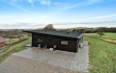 a small black house with two chairs on a patio at 3 Bedroom Stunning Home In Løgstrup in Løgstrup