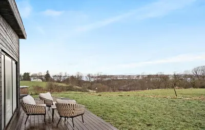 a deck with chairs and a table and a field at 3 Bedroom Stunning Home In Løgstrup in Løgstrup