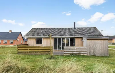 a small house with a wooden fence in a field at 2 Bedroom Cozy Home In Thisted in Thisted