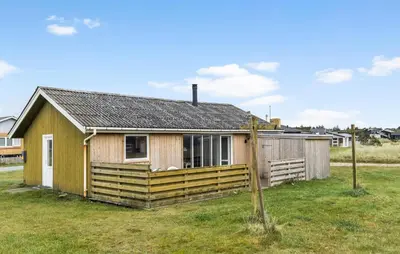 a small yellow house with a fence in a field at 2 Bedroom Cozy Home In Thisted in Thisted