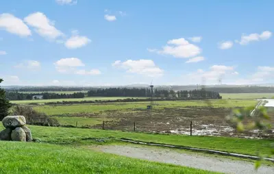 a grassy field with a windmill in the distance at Cozy Home In Hanstholm With Wifi in Hanstholm
