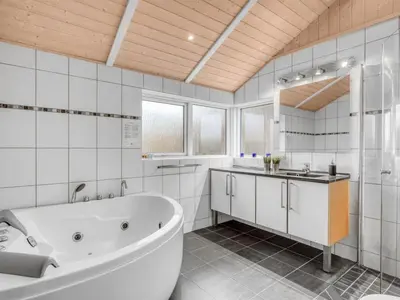 a white bathroom with a tub and a sink at Holiday Home Næwe - 10m to the fjord by Interhome in Roslev