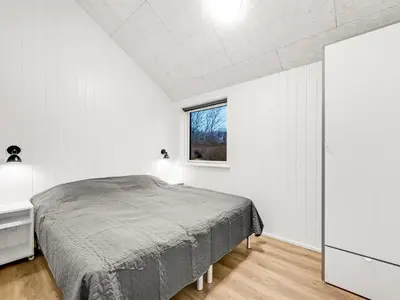 a white bedroom with a bed and a window at Holiday Home Grimar - 400m to the fjord by Interhome in Vemb
