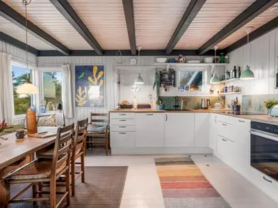 a kitchen with white cabinets and a table and chairs at Holiday Home Sella - 600m from the sea by Interhome in Blokhus