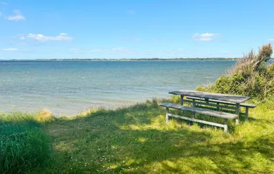 two benches sitting on the grass near the water at 2 Bedroom Amazing Home In Spøttrup in Spottrup