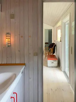 a kitchen with wood paneled walls and a white sink at A Gem In The Woods Close To The North Sea in Rødhus