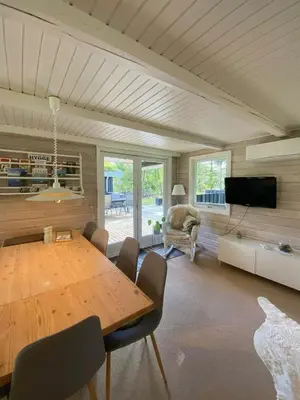a dining room with a large wooden table and chairs at Familievenligt Hus Nær Tranum Klitplantage in Pandrup