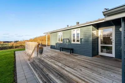 a wooden deck in front of a house at Beautiful Holiday Home With A Lovely View Of The Fjord And The Sea in Vestervig