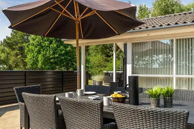a table with an umbrella on a patio at Lovely Holiday Home With Wilderness Bath And Space For 8 People in Pandrup