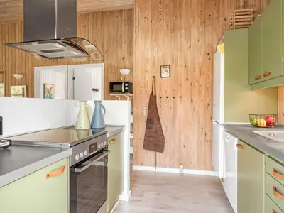 a kitchen with green and white cabinets and wooden walls at Holiday Home Elisenda - 2-2km from the sea by Interhome in Blokhus