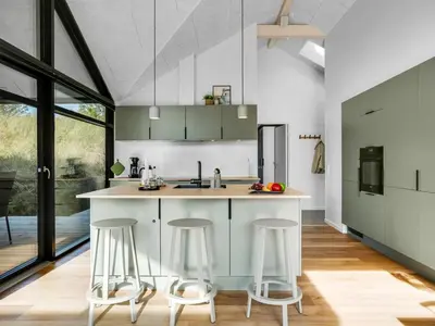 a kitchen with white cabinets and bar stools at Holiday Home Helga - 900m from the sea by Interhome in Blokhus