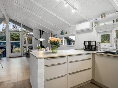 a kitchen with white cabinets and a vase of flowers at Holiday Home Gonda - 2km from the sea by Interhome in Saltum