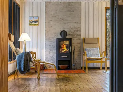 a living room with a fireplace and a chair at Holiday Home Star - 600m from the sea by Interhome in Løkken