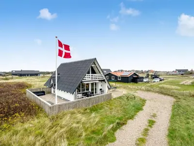 a house with a canadian flag in a field at Holiday Home Kaja - 150m from the sea by Interhome in Harboør