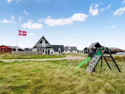 a playground in front of a house with a flag at Holiday Home Kaja - 150m from the sea by Interhome in Harboør
