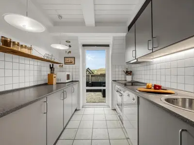 a kitchen with white cabinets and a sink and a door at Holiday Home Kaja - 150m from the sea by Interhome in Harboør
