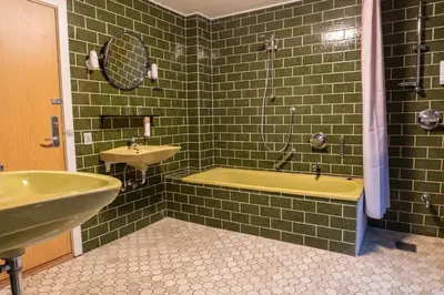 a green tiled bathroom with a tub and a sink at Villa Apartments Viborg in Viborg