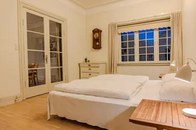 a bedroom with a bed and a table and a window at Villa Apartments Viborg in Viborg