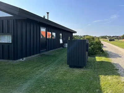 a black building with a fence in front of it at Architect-Designed Summer House In Agger in Vestervig