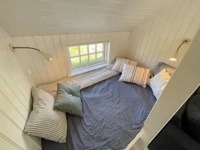 a bed in a tiny house with pillows at Home With Sauna Near Klitmøller in Thisted