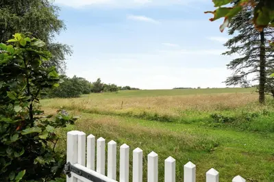 a white fence in a field next to a field at Nature-Close Home Near Beach At Limfjorden in Thyholm