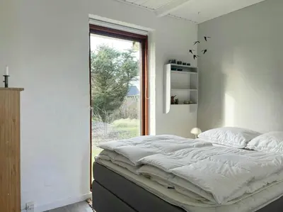 a bedroom with a large bed and a window at Cozy Summer House In Agger Near The North Sea in Vestervig
