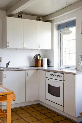 a kitchen with white cabinets and a stove top oven at Small House With View Of The Limfjord in Roslev