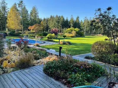a garden with a wooden walkway and a pool at Relax In The Countryside With Pool in Avlum